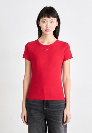 T-shirt rouge à manches courtes avec un corps ajusté, col rond et un petit logo sur la poitrine. Tissu lisse et extensible.