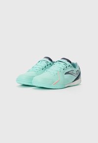 Scarpe da ginnastica verde menta con una tomaia testurizzata, accenti blu navy e una leggera striscia rossa. Presentano un profilo basso e un design con lacci.