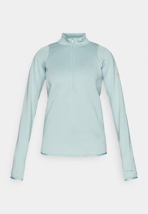 Svetlo modra dolga majica s puloverjem in pol-zadrgo spredaj, teksturirana tkanina, gladki poudarki ter logotip "Columbia" na prsih in rokavu.