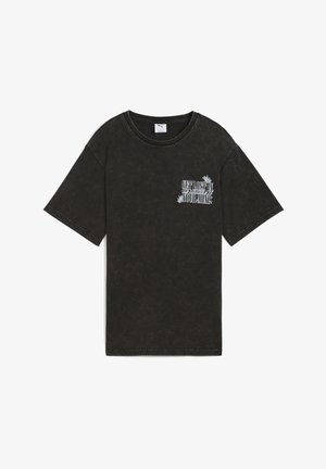 Schwarzes, distressed T-Shirt mit kurzen Ärmeln, auf der linken Brust mit weißem Text und floralem Design, das "VERLIER DICH IN DEINER MINE" liest.