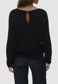 Pull en tricot noir avec un large col et un détail en forme de trou de serrure à l'arrière. Coupe ample avec des manches longues et un tissu texturé.