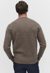 Ruskea villa-neule pyöreällä kauluksella, resorikohdistetut hihansuut ja helma. Kankaan pinta on pehmeä, muotoilu istuva ja klassinen siluetti.