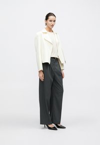 Hvid kort jakke, beige top, grå vidde bukser og sorte spidse hæle. Simpelt, skræddersyet design med en glat tekstur.