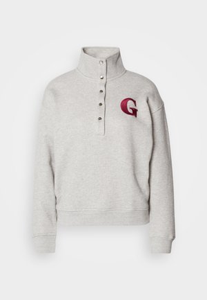Lys grå bomullsblanding hettegenser med høy krage, knappestolpe og brodert rød "G" på brystet. Ribbestrikkede mansjetter og nederkant.