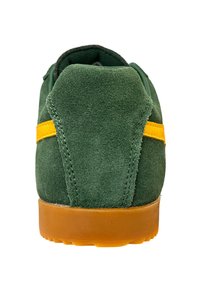 Sneaker verde in suede con punta arrotondata, evidenziata da una striscia gialla. Presenta una suola in gomma e dettagli di cucitura a contrasto.