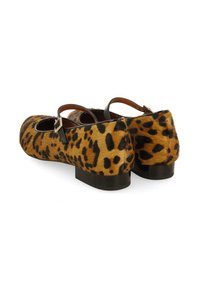 Zapatos planos con estampado de leopardo, con una textura similar al pelo, punta redondeada y delgados tirantes negros en el tobillo, que cuentan con un bajo tacón cubano.