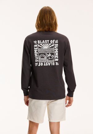 Long-sleeve black t-shirt with white graphic featuring sun and palm tree designs, text "BLAST OF SUMMER," round neckline, relaxed fit.
