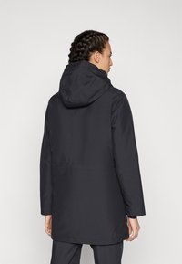 Parka noir imperméable avec capuche, conçu avec une coupe droite, des manches longues et une taille cintrée. Texture lisse, détails minimaux.