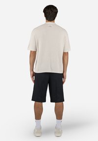 Beige ribbet skjorte med korte ærmer og rund hals, parret med sorte shorts. Sættet har en afslappet pasform og minimalistisk design.