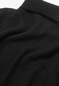 Suéter negro de punto con cuello alto acanalado, fabricado en un tejido suave y texturizado con un acabado liso y detalles de costura sutiles.