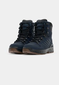 Hoge wandelschoenen in marineblauw synthetisch materiaal met zwart vetersysteem, getextureerde accenten en bruine rubberen zolen met grippatronen.