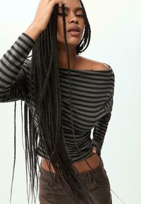 Langsleeve, off-shoulder top van grijs en zwart gestreepte stof. Beschikt over een strakke pasvorm, zachte textuur en ribgebreide manchetten.