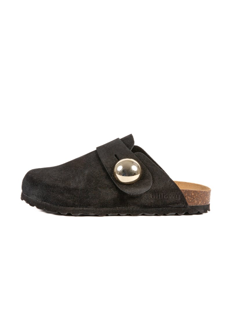Chaussure slip-on en suède noir avec un accent argenté rond et une semelle extérieure en liège plate. Dispose d'une large bande sur le cou-de-pied pour un maintien sécurisé.