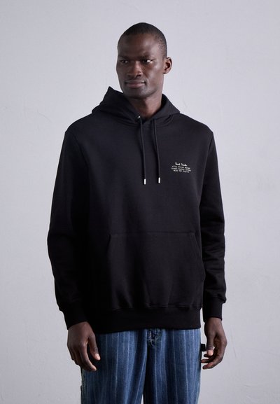 Sudadera con capucha negra, hecha de material suave, que presenta un bolsillo frontal, cordones y un sutil estampado gráfico en el pecho.