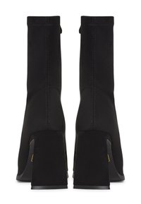 Black ankle boots with a soft suede finish, block heels, and visible stitching details. Minimalist design with a smooth, structured silhouette.