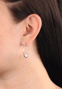 Silver hoops som har en böjd design med en polerad yta och en ensam vit pärla som accent längst ner.