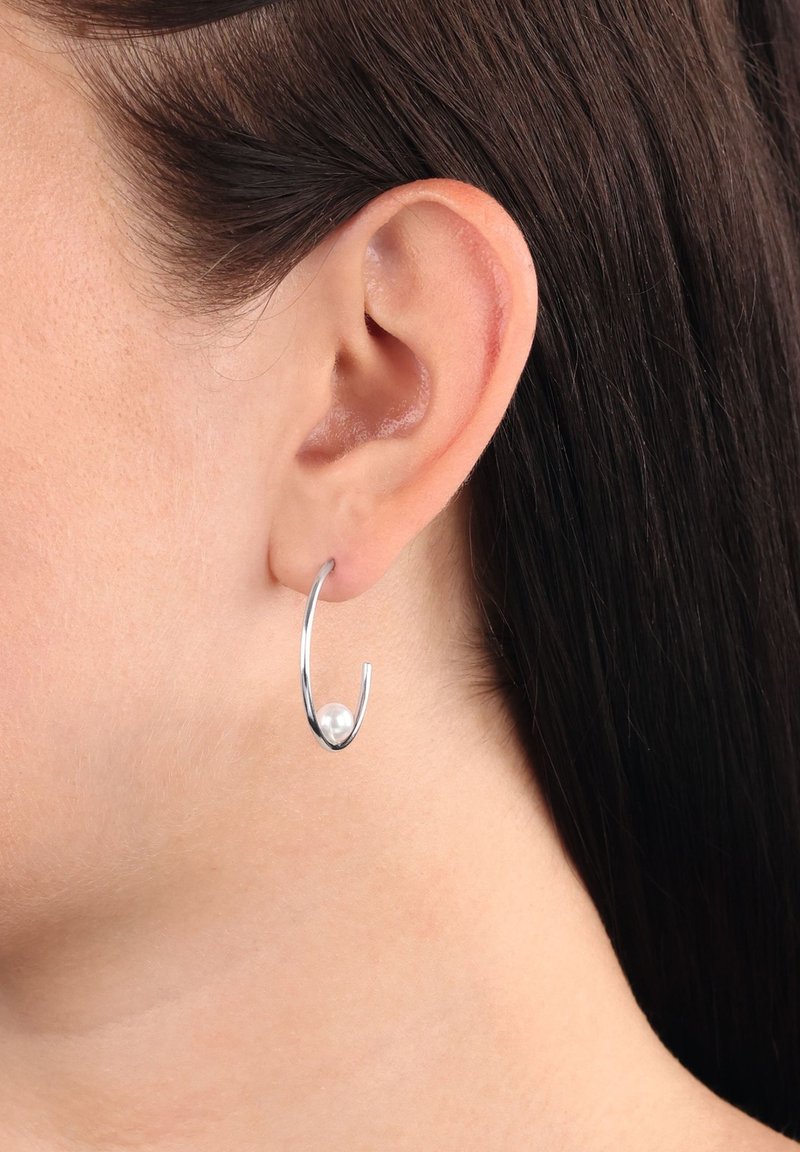 Silver hoops som har en böjd design med en polerad yta och en ensam vit pärla som accent längst ner.
