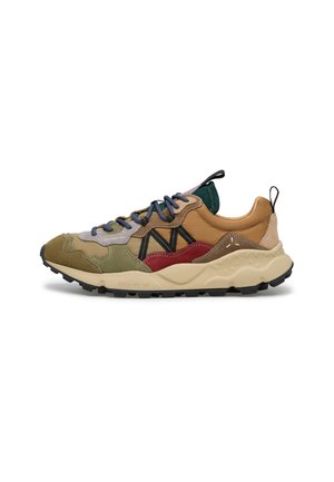 Scarpa sportiva multicolore con suola beige, una miscela di toppe verdi, marroni, rosse e beige, lacci blu e linguette nere sul tallone e sulla lingua.