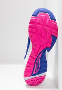 Bílé tenisky s modrými a růžovými akcenty. Silná gumová podrážka s výrazným růžovým a modrým designem, obsahující strukturované gripové vzory a viditelné logo.