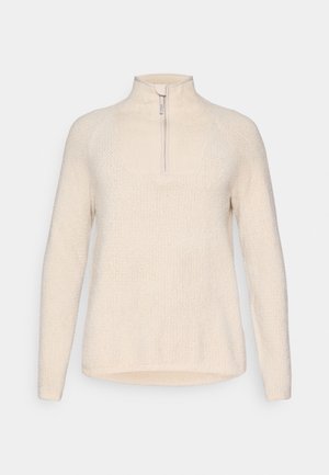 Sweter z okrągłym dekoltem w miękkim kremowym materiale z teksturowanym splotem. Posiada zamek błyskawiczny na ćwierć długości oraz długie rękawy, zapewniający luźny krój.