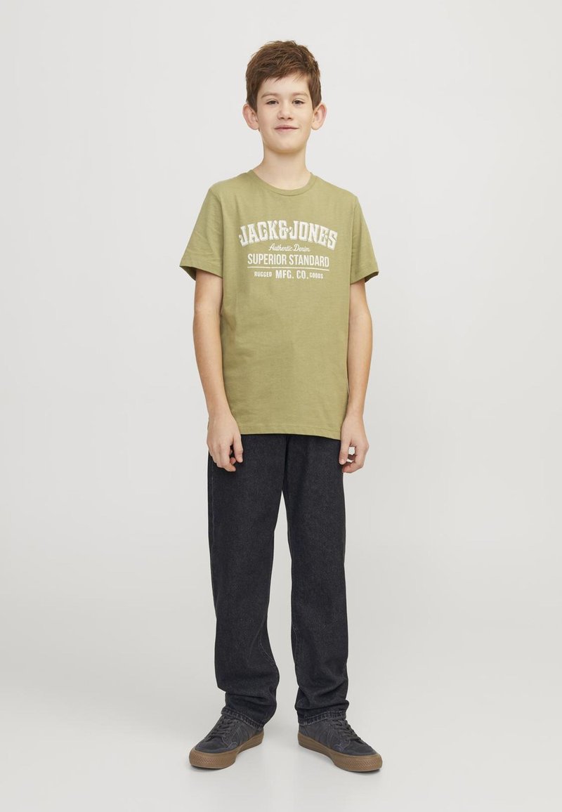 Zelena pamučna majica s bijelim natpisom "JACK & JONES" i "SUPERIOR STANDARD." Uparena s tamnosivim hlačama i sivim tenisicama.