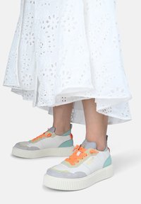 Weiße Low-Top-Sneaker aus einer Kombination von grauem Wildleder und Leder, mit orangen Schnürsenkeln, türkisfarbenen Akzenten und strukturiertem Sohlendesign.