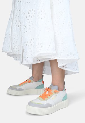 Białe niskie sneakersy z mieszanką szarego zamszu i skóry, pomarańczowe sznurowadła, turkusowe akcenty oraz teksturowana podeszwa.
