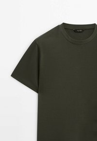 Oliwkowy t-shirt z krótkim rękawem, wykonany z bawełny, posiada okrągły dekolt oraz gładką, równomierną teksturę. Brak widocznych wzorów czy akcentów.