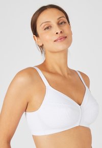 Sostén blanco con tela suave, tirantes ajustables y un intrincado bordado en el centro y los bordes superiores.