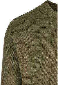 Pull tricoté vert olive avec encolure ronde côtelée et motif de points texturés visibles sur l'épaule et le haut de la manche.