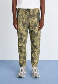 Camo-mønstret cargo-bukser i olivengrøn med lynlåslommer, elastisk talje og tapered ben. Holdbart stof med en struktureret overflade.