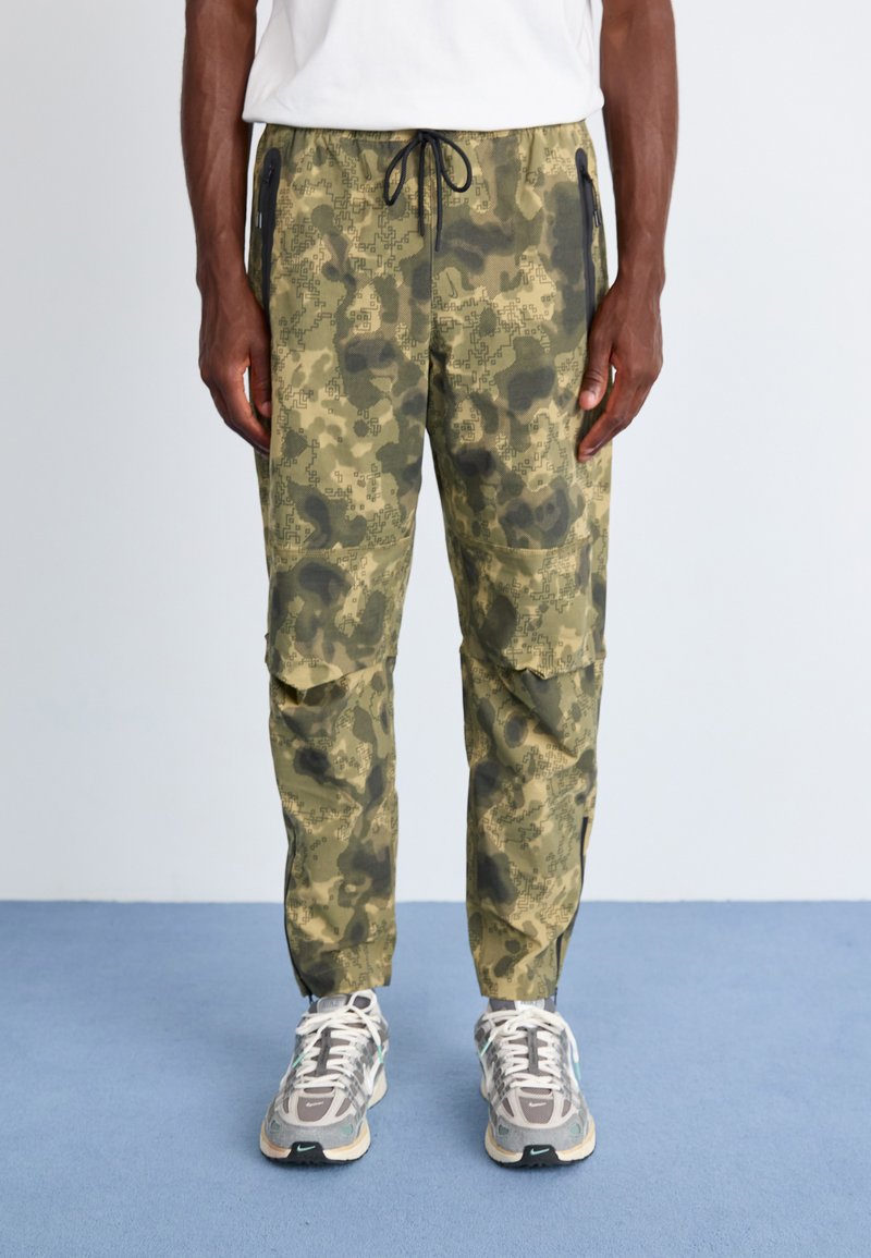 Camo-mønstret cargo-bukser i olivengrøn med lynlåslommer, elastisk talje og tapered ben. Holdbart stof med en struktureret overflade.