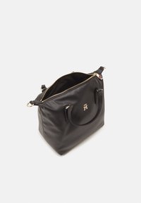 Czarna skórzana torebka z złotym zamkiem częściowo otwartym, podwójnymi uchwytami i małym złotym emblematem z przodu, umieszczona na białym tle.