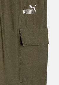 Pantalons cargo vert olive avec une poche à rabat et un logo Puma brodé blanc. Fabriqués dans un tissu lisse avec une texture légèrement brillante.