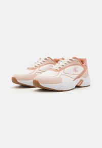 White and peach-colored sneakers with mesh and synthetic overlays, featuring a textured rubber sole and pink accents on the heel.