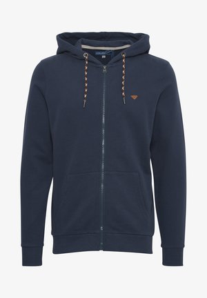 Tamno plava zip-up dukserica od mekanog materijala, s kapuljačom na vezanje i dva prednja džepa, sa kontrastnim uzorkovanim vezicama i detaljem logotipa.