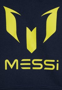 Felpa blu navale con un logo giallo prominente, caratterizzato da forme nitide e angolari e il testo "MESSI" in un carattere audace. Texture liscia.