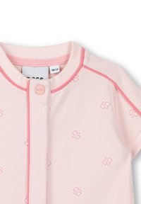 Bodysuit pour bébé rose clair avec des bordures roses contrastantes, présentant un tissu texturé et un motif de logo de marque répété. Fermeture à boutons-pression au niveau du col.