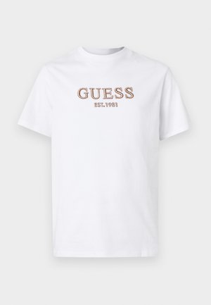 Weißes Baumwoll-T-Shirt mit kurzen Ärmeln, das auf der Vorderseite das gestickte "GUESS"-Logo und das Detail "EST. 1981" in Braun zeigt. Normale Passform.