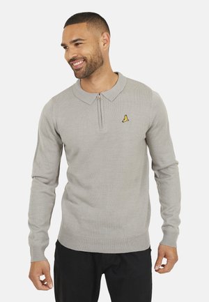 Maglione grigio a maniche lunghe con zip e colletto. Presenta un logo giallo sul petto. Realizzato in un tessuto a maglia testurizzata. Pantaloni neri.
