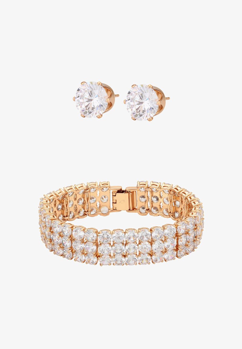 Armbånd og stiftøreringe i guldfarve med klare, fasetterede krystaller. Armbåndet har et fleksibelt design med en sikker lås og viser flere rækker af ædelsten.