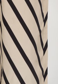 Beige szövet, erőteljes fekete átlós csíkokkal; sima textúra; öltöny szabás, tiszta élek és varratok; modern dizájnelem.