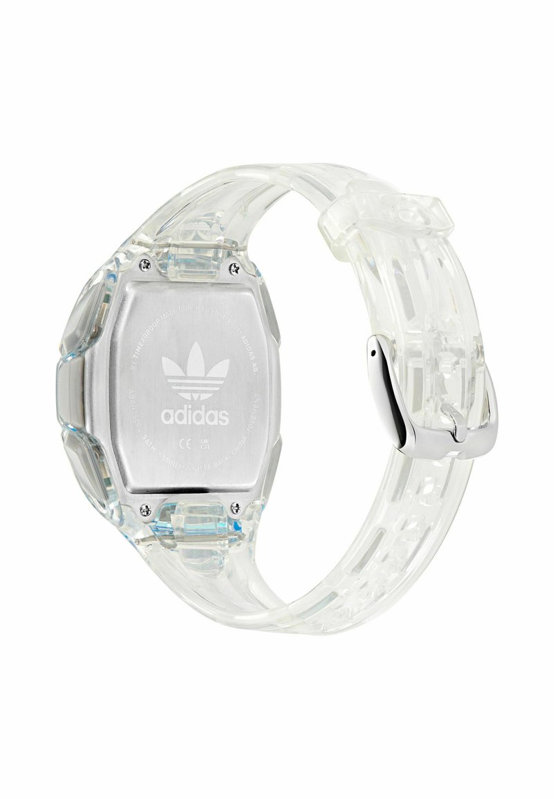 Reloj digital transparente con una esfera octagonal, parte posterior metálica plateada y una correa transparente, con el logotipo de Adidas.
