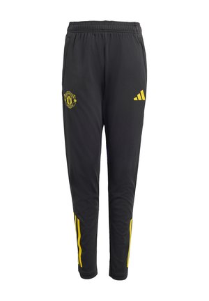 Pantalon de sport noir avec logo jaune de Manchester United, logo Adidas et bandes jaunes près des chevilles. Taille élastique et jambes fuselées.