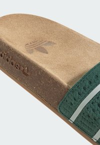 Zelený látkový pásek s perforovanou texturou. Korková stélka, hnědá podrážka, obsahuje logo Adidas a trojlístkový vzor. Plackový design.