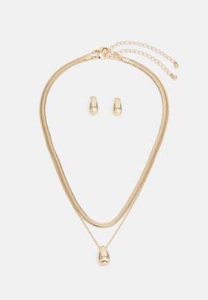 Conjunto de joias em ouro com um colar em camadas com um pingente em forma de gota e brincos de botão combinando, tudo em acabamento polido.