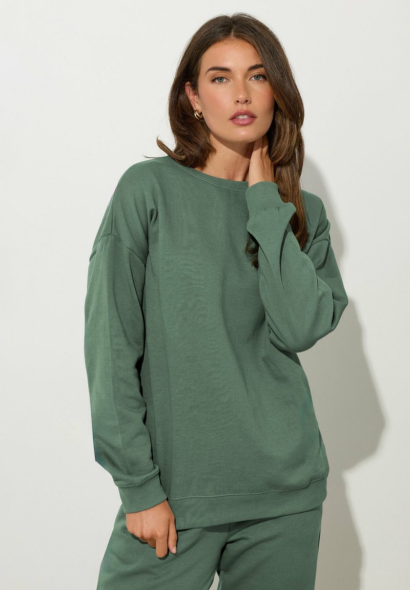 Sudadera verde hecha de suave algodón, con un corte holgado, cuello acanalado y mangas largas. Diseño sencillo sin patrones ni acentos.