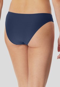 Navyblauer Bikiniunterteil, mit strukturiertem Stoff und subtilen geometrischen Mustern, mittelhoher Schnitt und breiten Seitenbändern für zusätzlichen Komfort.
