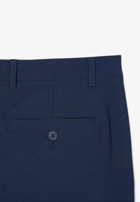 Pantalones azul marino con una textura suave. Presentan un bolsillo trasero con un botón redondo azul marino. La cinturilla es lisa con pasadores para cinturón.