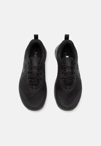 Zapatillas deportivas negras con parte superior de malla, punta redonda y cordones planos. Presentan una pestaña en el talón y un branding sutil.